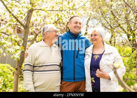 Adult son with his elderly parents outdoors in a natural setting. Stock Photo