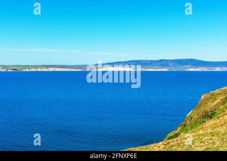 View of Drakes Bay calm water and coastline with dramatic white sandstone cliffs on horizon from Point Reyes Headlands Stock Photo