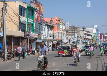 Busy road in central Jaffna with pedestrians, men riding bicycles and  shopfront advertising, Northern Province, Sri Lanka Stock Photo