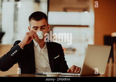 Happy business man sitting at cafeteria with laptop and smartphone Stock Photo