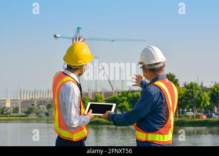 Two engineer worker tablet working on site construction, asian man architecture builder building surveyor professional Stock Photo
