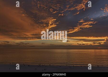 Dramatic orange sunset over the Gulf of Mexico with people on the beach at Marco Island, Florida, during COVID-19 quarantine Stock Photo