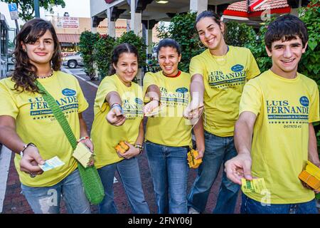 Miami Florida,Little Havana,Calle Ocho,Hispanic teens teenagers volunteers,handing out free campaign material wearing matching tee shirts boys girls Stock Photo