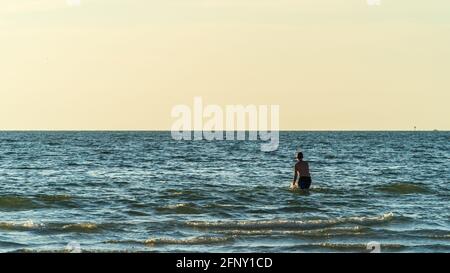 Youth splashes in blue waters against clear sky Stock Photo