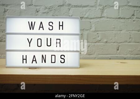 Wash Your Hands word in light box with space coy on white brick and wooden shelves background Stock Photo