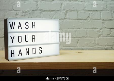 Wash Your Hands word in light box with space coy on white brick and wooden shelves background Stock Photo