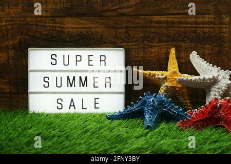 Summer Sale text in light box and starfish on wooden background Stock Photo