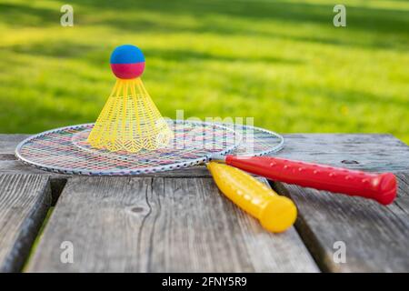 Badminton game rackets and shuttlecock on wooden table with green grass backgroud in the park on a sunny summer day. Active lifestyle concept. Fun out Stock Photo
