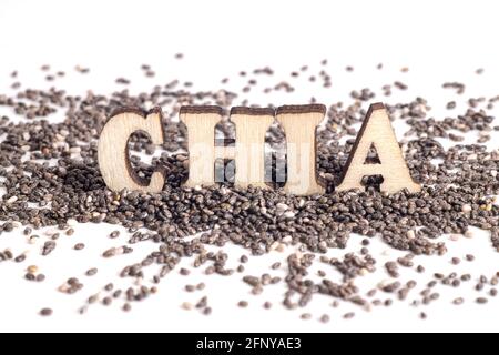 Word CHIA made of wooden letters standing on chia seeds scattered on a white table Stock Photo