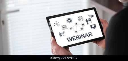 Webinar concept shown on a tablet held by a man Stock Photo