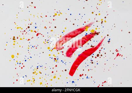 Abstract composition. Chaotic drops and smears of paint on white paper. Yellow, red and blue dots and splashes on paper. Three random paint strokes. M Stock Photo