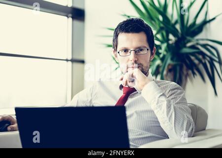 Portrait of businessman working on laptop computer Stock Photo