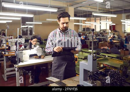 Experienced craftsman working in a leather goods factory is preparing to make new belts. Stock Photo