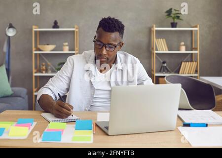 Young african american man sitting at desk working on laptop computer from home Stock Photo