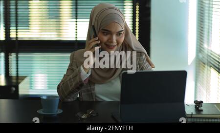 Portrait of young muslim businesswoman talking on the phone while working in office room Stock Photo