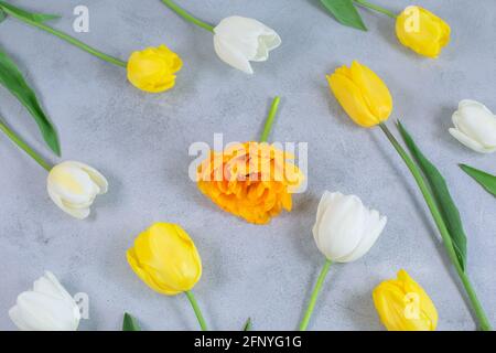 Floral pattern made of White and yellow tulips, green leaves on white background. Floral pattern. Pattern of flowers. Flowers pattern texture. Flat lay, top view. Stock Photo