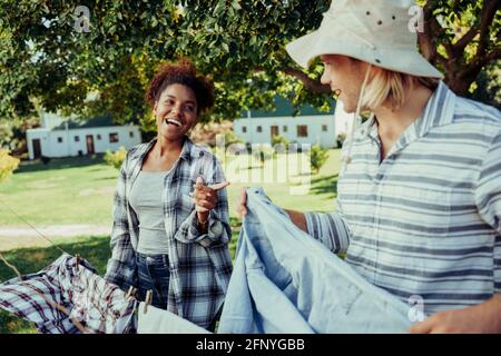 Mixed race couple hanging up laundry on washing line in backyard  Stock Photo