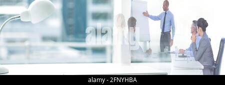 Composition of office desk with lamp over businessman giving presentation in office Stock Photo
