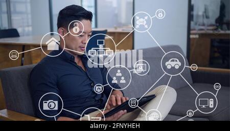 Composition of network of connections with icons over man using tablet Stock Photo