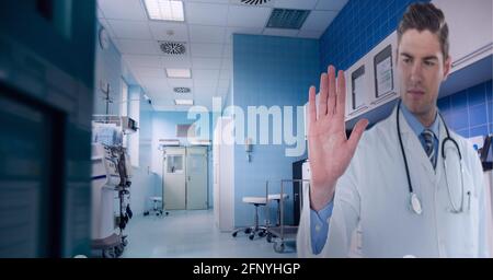 Caucasian male doctor touching invisible screen against hospital in background Stock Photo