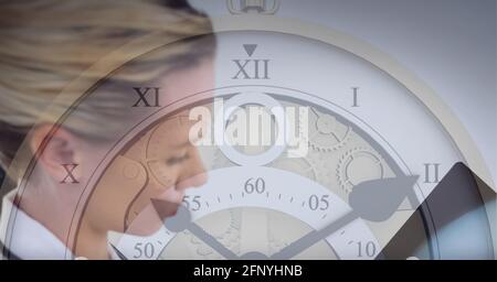 Close up of clock against caucasian female doctor examining x-ray report Stock Photo