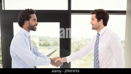 Composition of businessmen shaking hands in office Stock Photo