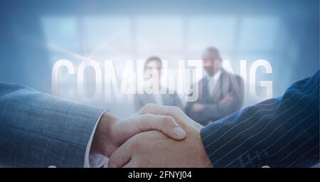 Computing text against mid section of two businessmen shaking hands against businesspeople standing Stock Photo