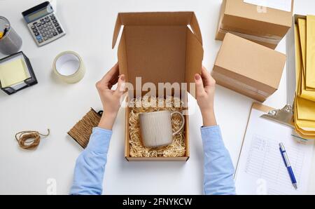 hands packing mug to parcel box at post office Stock Photo
