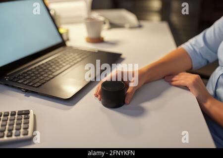 hand using smart speaker at night office Stock Photo