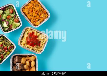 Take away healthy food in foil boxes on blue background Stock Photo