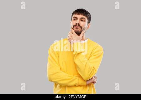 thinking young man in yellow sweatshirt Stock Photo