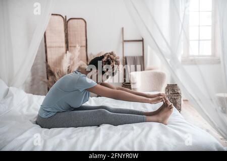 Woman sitting on bed with head bowed to feet Stock Photo