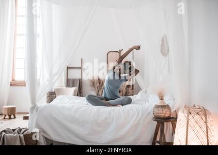 African American woman sitting in lotus position on bed Stock Photo