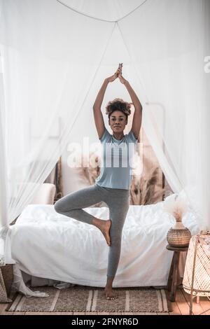 Woman doing yoga standing in bedroom Stock Photo