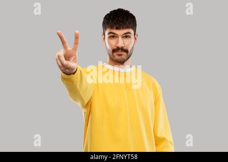 young man showing peace over grey background Stock Photo