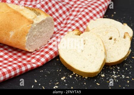 rustic crusty white bread lying on black slate on red white towel in the kitchen Stock Photo