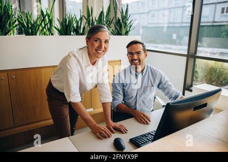 Happy manager and coworker working together and looking at camera. businesswoman with coworker smiling at camera in office Stock Photo