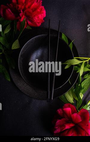 Overhead view of an Asian place setting on a table with red peony flowers Stock Photo