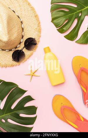 Flat composition with beach holiday accessories and monstera leaves on pink background. Stock Photo