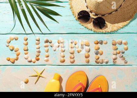 The inscription from seashells and beach accessories on a colored background, summer background. Stock Photo