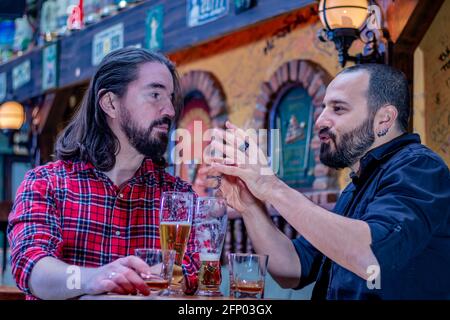 Two male friends drinking whiskey and beer together at the pub. They are happy and drunk and they are talking to each other. Stock Photo