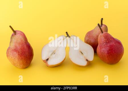 William Max Red Bartlett pear, three whole pears and one cut in half, isolated on yellow background, copy space Stock Photo