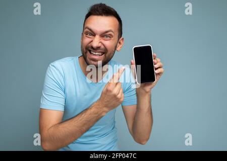 Photo of handsome crazy emotional smiling adult male person good looking wearing casual outfit standing isolated on background with copy space holding Stock Photo
