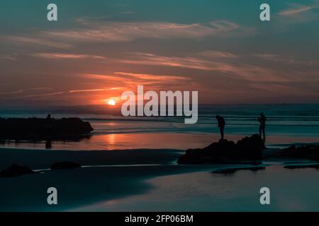 Sunset on the sea with some people wandering around on the beach, peoplle on the beach. Stock Photo