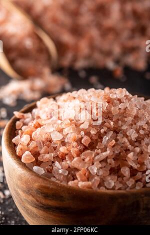 Himalayan rock salt in a wooden bowl, on a dark surface. Stock Photo