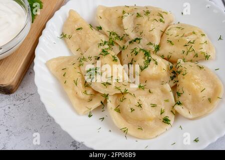 Dumplings with potatoes with green dill. Varenyky, vareniki, pierogi, pyrohy. Stock Photo
