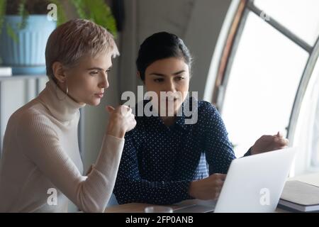 Multiracial female employees brainstorm on laptop in office Stock Photo