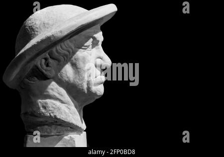 Black and white photo in close-up on grumpy face in profile of statue of senior man with a hat Stock Photo