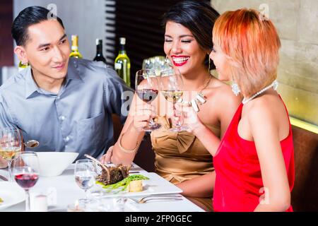 Asian friends, two couples, dining in fancy restaurant eating good food and drinking wine Stock Photo