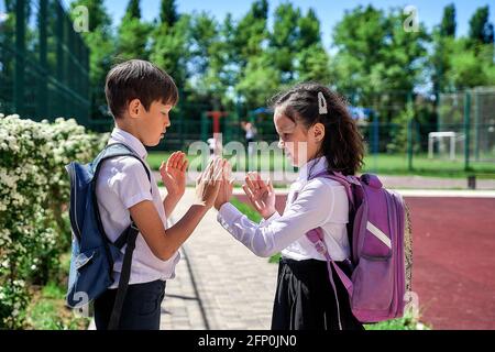 two students in a white shirt with satchels play in the school yard Stock Photo